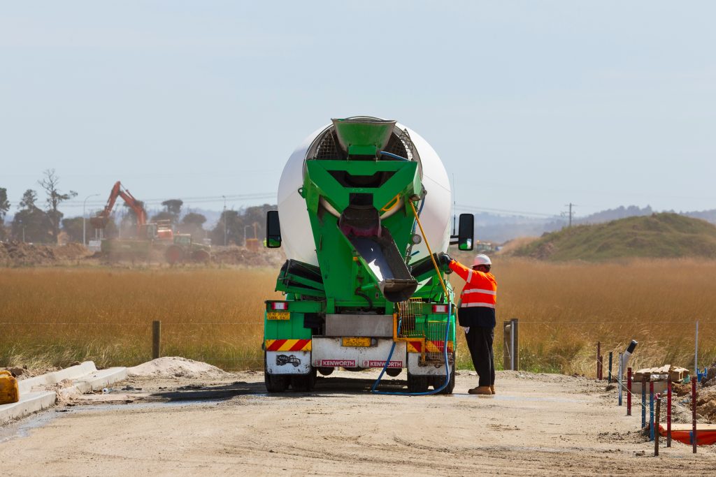 A self-loading concrete mixer truck on a construction site, preparing to mix and pour concrete.